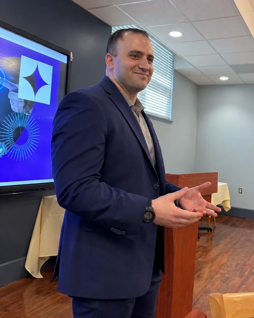 Dan Pace, founder of Genuine Technologies, speaking at an event beside a presentation screen